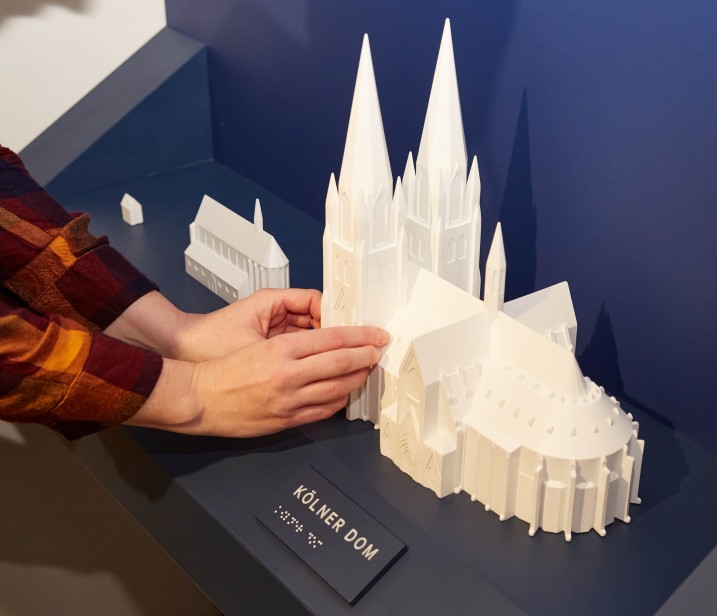 Bei dem inklusiven Panel können Tastmodelle von einem Haus, einer Kirche und dem Kölner Dom mit den Händen erforscht werden.