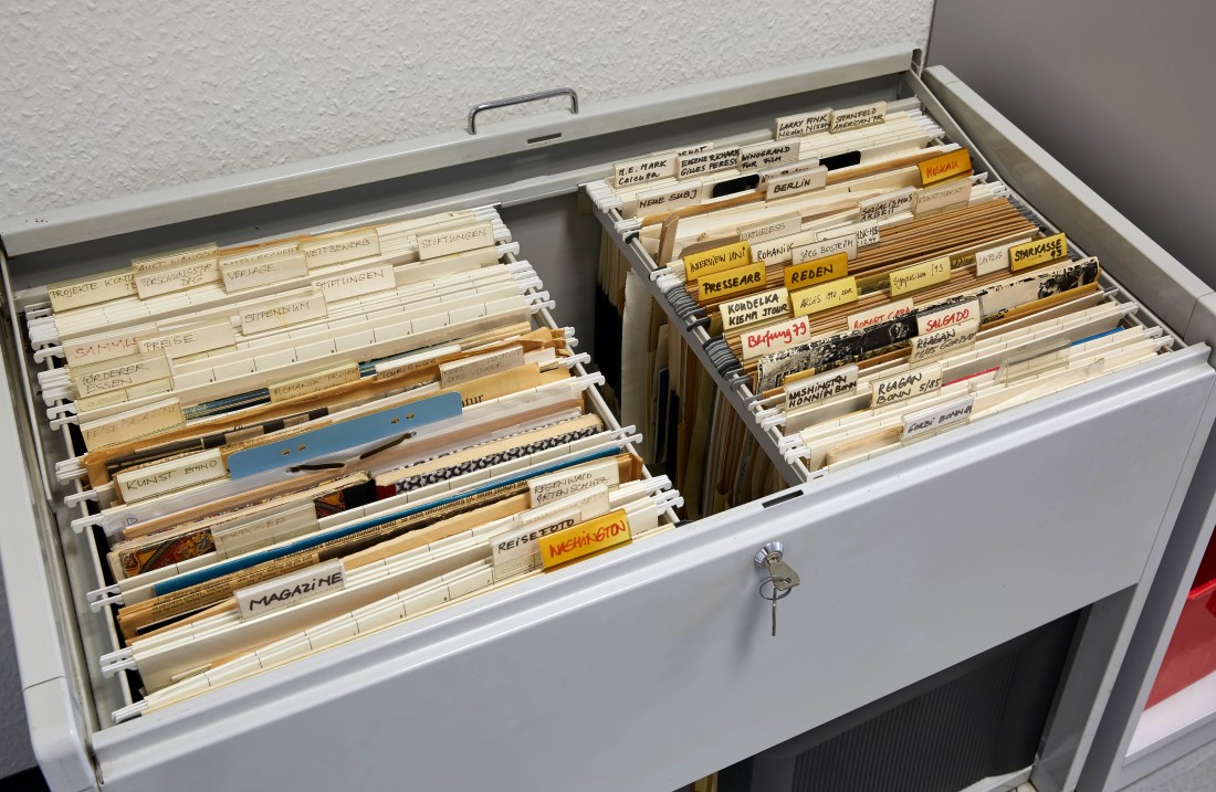 In einer geöffneten Schublade sind Akten und Archivmaterial abgelegt, sortiert und beschriftet.