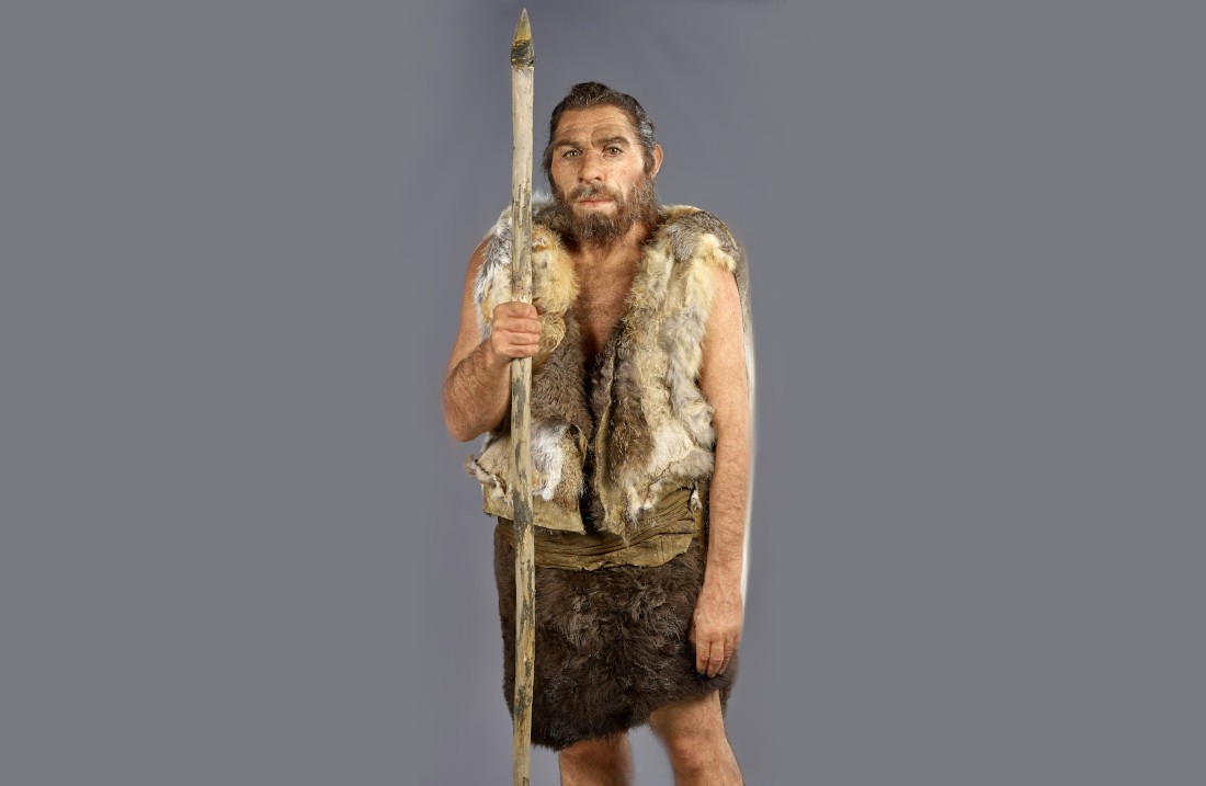 Die Rekonstruktion des Neandertalers. Ein Mann mit Fellweste, Lederkleidung und einem Speer.