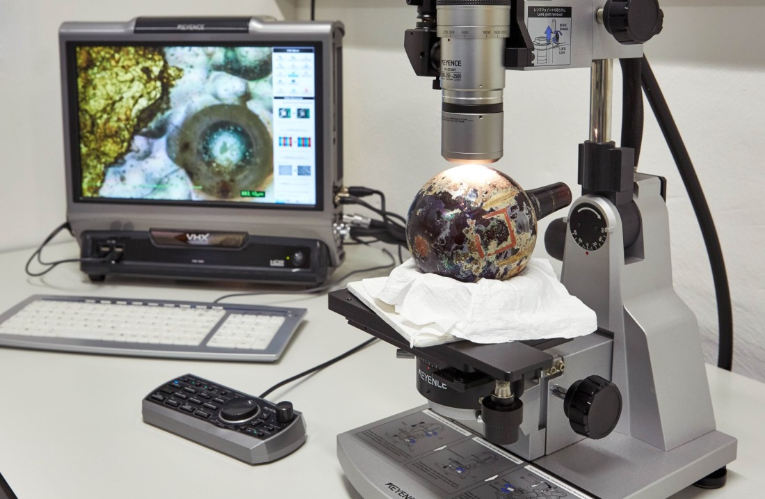 Vor der Restaurierung werden mit einem Mikroskop Untersuchungen vorgenommen.