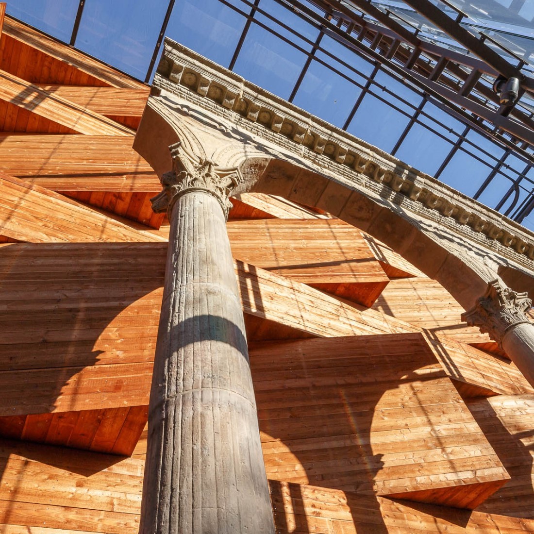 Blick an der Holzfassade des Museums entland. Davor steht ein römischer Bogen. Foto: J. Vogel, LVR-LandesMuseum Bonn.
