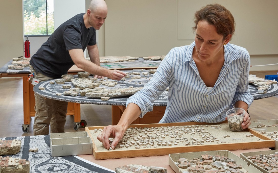 Eine Restauratorin und ein Restaurator arbeiten am Medusen-Mosaik.