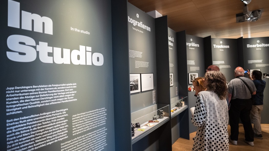 Besuchende schauen sich den Bereich "Im Studio" der Ausstellung "Jupp Darchinger. Das Auge der Republik" an.
