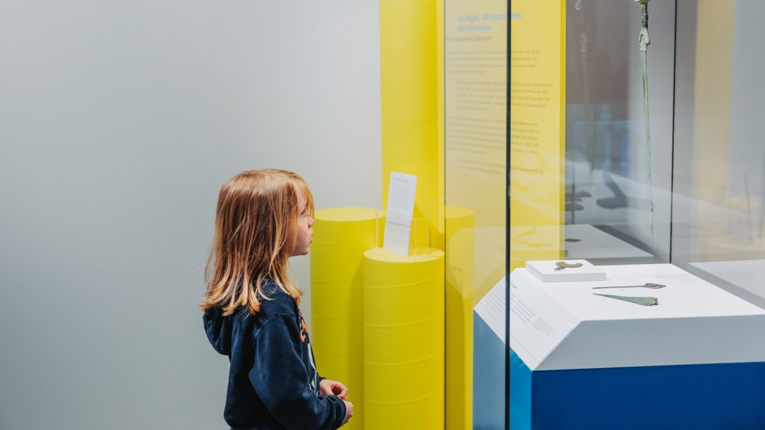 Ein Kind betrachtet eine Vitrine der Präsentation "Der Rhein. Leben am Fluss"
