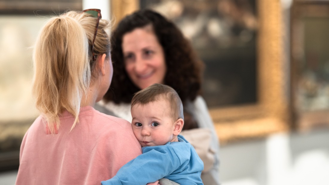 Eine Frau hält ein Baby auf dem Arm und ist im Gespräch. 