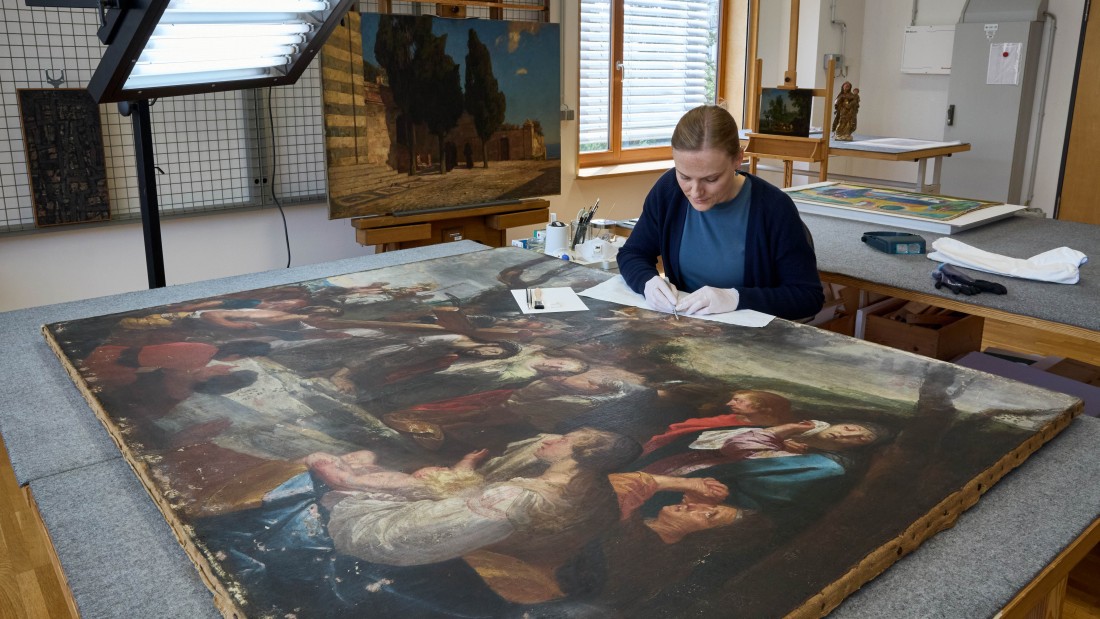 Eine Restauratorin des Landesmuseums arbeitet am Gemälde. 