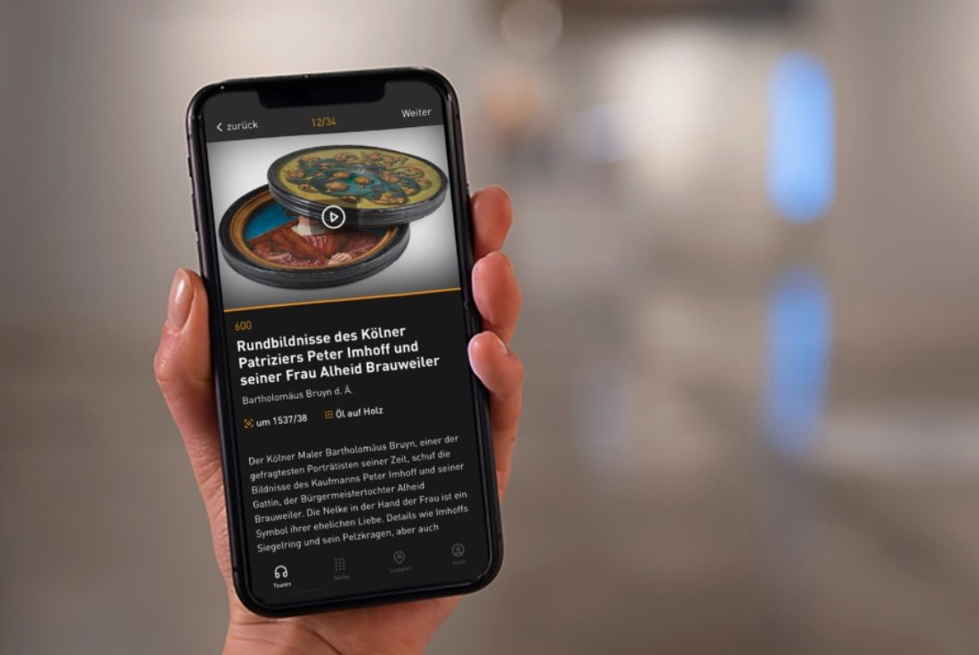 Eine Hand h&auml;lt ein Handy, das den Mediaguide des Landesmuseums zeigt.