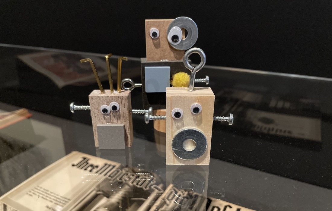 Selbstgebastelte Roboter sind auf einer Ausstellungsvitrine platziert.