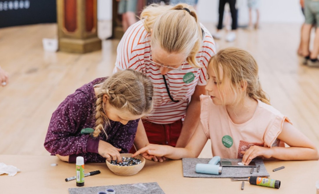 Eine Mutter mit zwei Kindern an einer Mitmachstation zum Escape Game "Nachtwache"