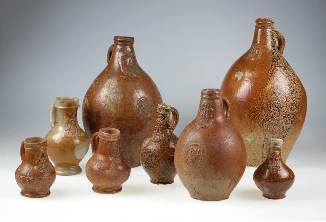 Eine Reihe von kleinen und gro&szlig;en Bartmannkr&uuml;gen mit brauner Glasur.