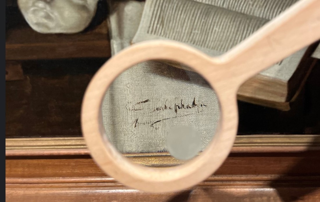 Eine Lupe vor einer Signatur eines Gem&auml;ldes.