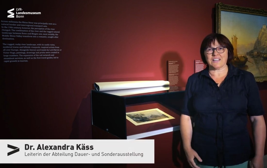 Video Still mit Ausstellungsdirektorin Alexandra K&auml;ss vor der Vitrine mit der Grafik von William Turner.