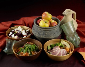 Auf einem Tisch stehen verschiedene Gefäße mit mittelalterlichen Speisen.