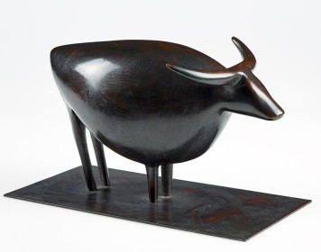 Einfache geometrische Formen bilden die Skulptur eines schwarzen Rinds. Es steht auf einer glatten flachen Platte.