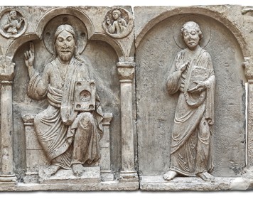 Vier Steintafeln zeigen mittig Christus mit dem Codex flankiert von Aposteln. 