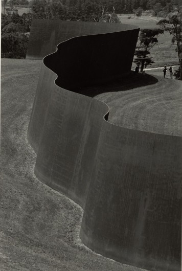 Eine Schwarz-Weiß-Fotografie einer riesigen metallenen Skulptur in einer Landschaft.