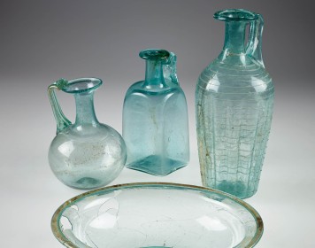 Römische Glasgefäße vor grauem Hintergrund