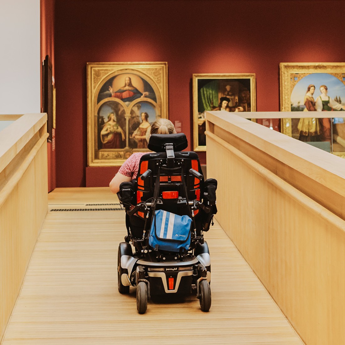 Eine junge Frau im Rollstuhl fährt eine Rampe in der Dauerausstellung des Landesmuseums hoch.